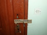 Drzwi wejściowe z plombą, na której jest napis &quot;POLICJA&quot;.
