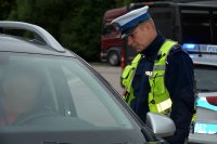 Policjant w umundurowaniu służbowym kontroluje samochód