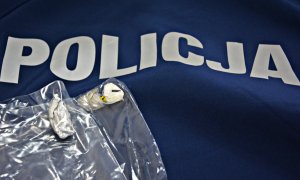 Na niebieskiej bluzie z napisem POLICJA leżą dwa zawiniątka