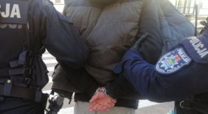 Policjanci prowadzą zakutego w kajdanki mężczyznę