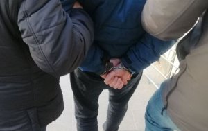 Policjanci prowadzą zatrzymanego skutego kajdankami