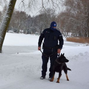 Policjant z psem służbowy podczas patrolu w pobliżu  jeziora w śnieżnej scenerii