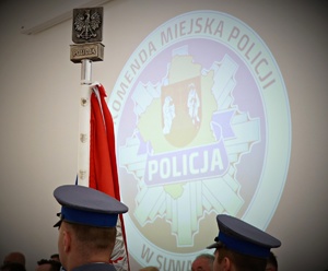 Poczet sztandarowy na tle napisu KMP w Suwałkach