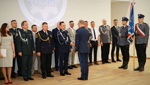 Komendant Miejski Policji w Suwałkach ściska dłoń Zastępcy Komendanta Miejskiego Policji w Białymstoku, w tle zaproszeni goście