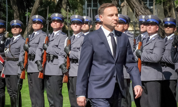 Prezydent Andrzej Duda w tle policjanci w umundurowaniu galowym.