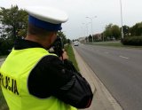 Policjant ruchu drogowego dokonuje pomiaru prędkości jadących samochodów