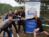 Pięć osób w strojach sportowych z medalami na szyjach na tle rolap-u Komendy Miejskiej Policji w Suwałkach