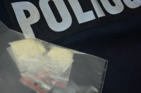 Biały proszek w torebkach foliowych na bluzie policyjnej