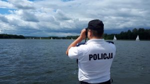 Policjant, patrzący przez lornetkę na jezioro