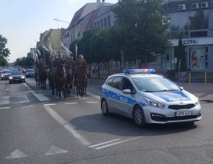 radiowóz zabezpiecza przemarsz żołnierzy na koniach
