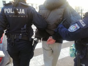 Policjanci prowadzą skutego w kajdanki mężczyznę