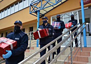 Policjanci znoszą po schodach paczki