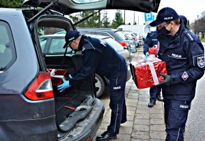 Policjanci wkładają paczki do samochodu