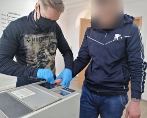 Policjant pobiera odciski palców od mężczyzny