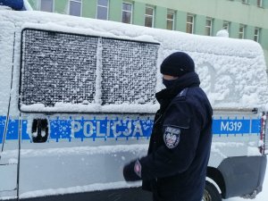 Policjant na tle zaśnieżonego radiowozu