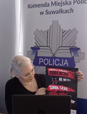 Kobieta trzyma w rękach plakat podczas zajęć online