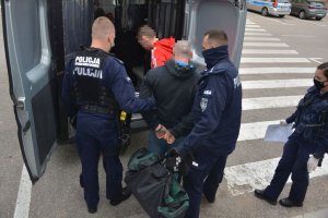 Policjanci przygotowują mężczyzn do transportu