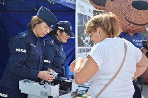 Policjantka pokazuje kobiecie walizkę- pakiet edukacyjny