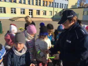 Policjantka wręcza odblaski dzieciom