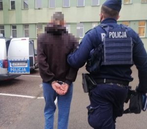 Policjant prowadzi zatrzymanego mężczyznę