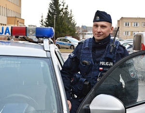 Policjant w umundurowaniu ćwiczebnym przy radiowozie