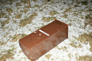 Brązowa skrzynia z napisem ofiary leży na zaśnieżonym trawniku