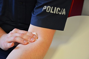 Policjant pod oddaniu krwi przytrzymuje wacikiem miejsce wkłucia