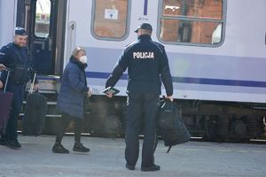 Policjanci z pasażerami na tle pociągu