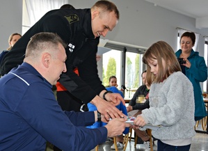 Policjant, strażnik graniczny wręcza nagrody dziewczynce