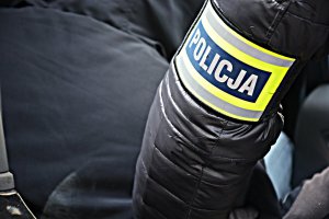 ręka z opaską z napisem POLICJA