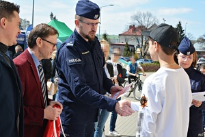 Komendant w towarzystwie dwóch mężczyzn wręcza nagrodę laureatom