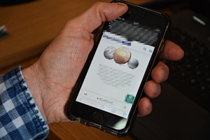 Mężczyzna trzyma w ręku telefon komórkowy, na ekranie kryptowaluty