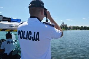 Policjant obserwuje jezioro przez lornetkę