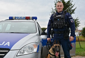 Policjant z psem przy radiowozie