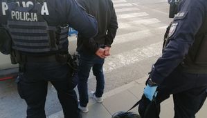 Policjanci i zakuty w kajdanki mężczyzna
