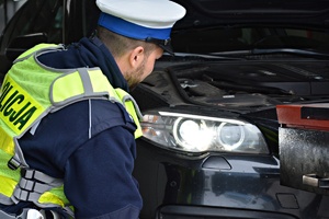 Policjanci, wspólnie z pracownikami stacji diagnostycznej sprawdzają światła samochodu