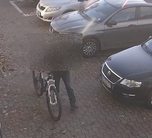 widok z monitoringu człowiek idzie z rowerem i samochody