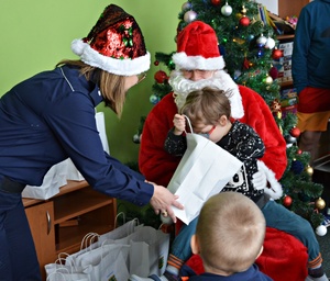 Policjantki i uczniowie przekazują dzieciom paczki świąteczne