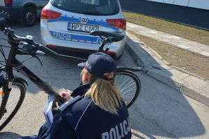 Policjantka znakuje rower w tle radiowóz