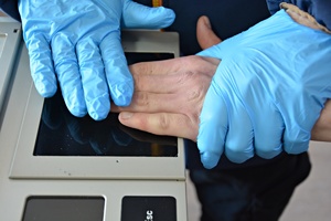 Technik kryminalistyki pobiera daktyloskopię zatrzymanemu