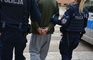 Policjanci prowadzą mężczyznę skutego w kajdanki