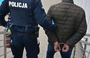 Policjant prowadzi zatrzymanego mężczyznę