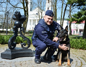 Policjant z psem służbowym w parku, przy zegarze słonecznym