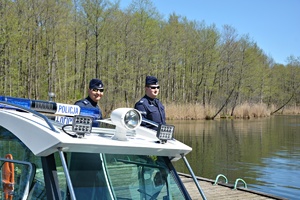Policyjni wodniacy przy policyjnej łodzi, w tle jezioro
