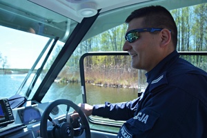 policjant w łodzi służbowej patroluje jezioro