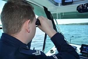 Policyjna łódź na wodzie, policjanci obserwują pływające jednostki