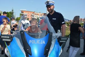 Policjant przy motorze na którym siedzi chłopczyk