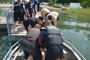 Policjanci i ratownicy pomagają mężczyźnie na łódce
