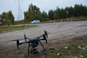 dron na drodze w tle przejazd kolejowy i radiowóz