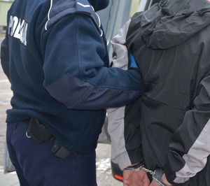 Policjant doprowadza zatrzymanego